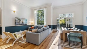 Ein Wohnzimmer mit grauem Sofa, einer Poolbillardkugel und einem großen Fenster.
