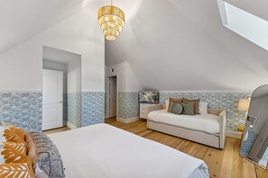 A bedroom with a bed, a sofa, a TV, and a ceiling light. - Golf Sim Pickleball Theater Sauna Games Sleeps 24 (Hilton Head Island)