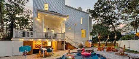 A two-story house with a covered patio, a swimming pool, and outdoor seating.