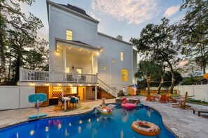 A two-story house with a covered patio, a swimming pool, and outdoor seating. - Golf Sim Pickleball Theater Sauna Games Sleeps 24 (Hilton Head Island)