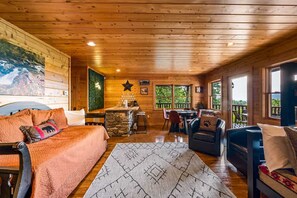 A cabin interior with a wooden ceiling, a dining area, a living room with a sofa and a rug, and a kitchen area. - Private Mtn Views Movie Theater Hot Tub Pool Table (Sevierville)