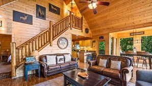 Geräumiges Cabin-Interieur mit Holzboden, einer Wendeltreppe, Ledersofas, einem Couchtisch und Blick ins Freie.