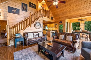 Geräumiges Cabin-Interieur mit Holzboden, einer Wendeltreppe, Ledersofas, einem Couchtisch und Blick ins Freie.