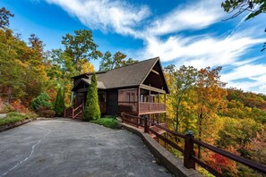 A cabin with a porch and a staircase leading up to it, surrounded by trees with autumn foliage. - Private Mtn Views Movie Theater Hot Tub Pool Table (Sevierville)
