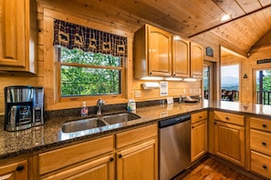 A kitchen with wooden cabinets, a stainless steel sink, and a dishwasher. - Private Mtn Views Movie Theater Hot Tub Pool Table (Sevierville)