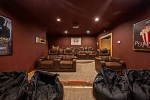 A home theater room with multiple reclining chairs, a popcorn machine, and a sign indicating a ticket booth. - Private Mtn Views Movie Theater Hot Tub Pool Table (Sevierville)