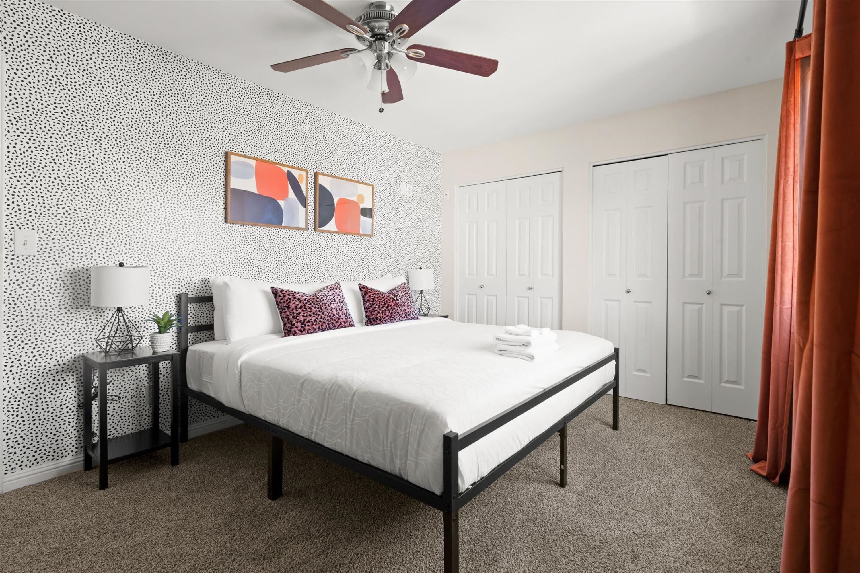 A bedroom with a bed, a nightstand, a ceiling fan, and a wall with a speckled pattern.