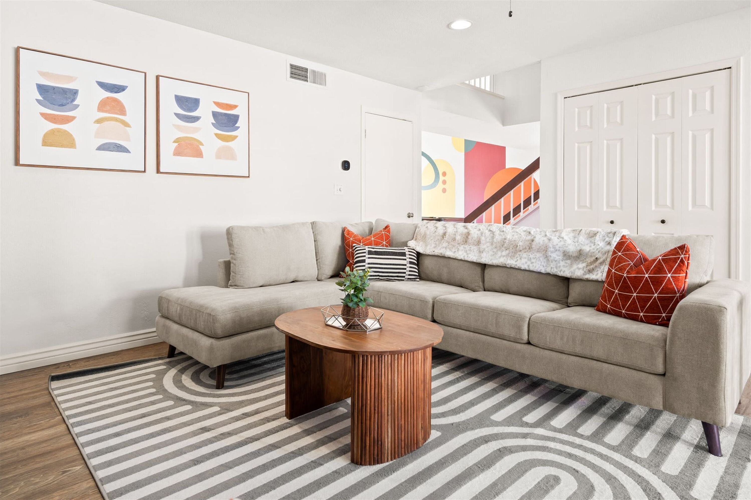 Un salon moderne avec un canapé d’angle, une table basse et un tapis à rayures.
