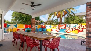 Eine Außenpatio mit Pool, roten Stühlen und einem Wandgemälde.