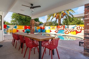 An outdoor patio with a pool, red chairs, and a mural on the wall. - The Retro Pool Hot Tub Basketball Games (Mesa)