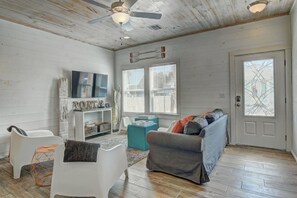 Uma sala de estar com ventilador de teto, lareira, sofá e televisão.