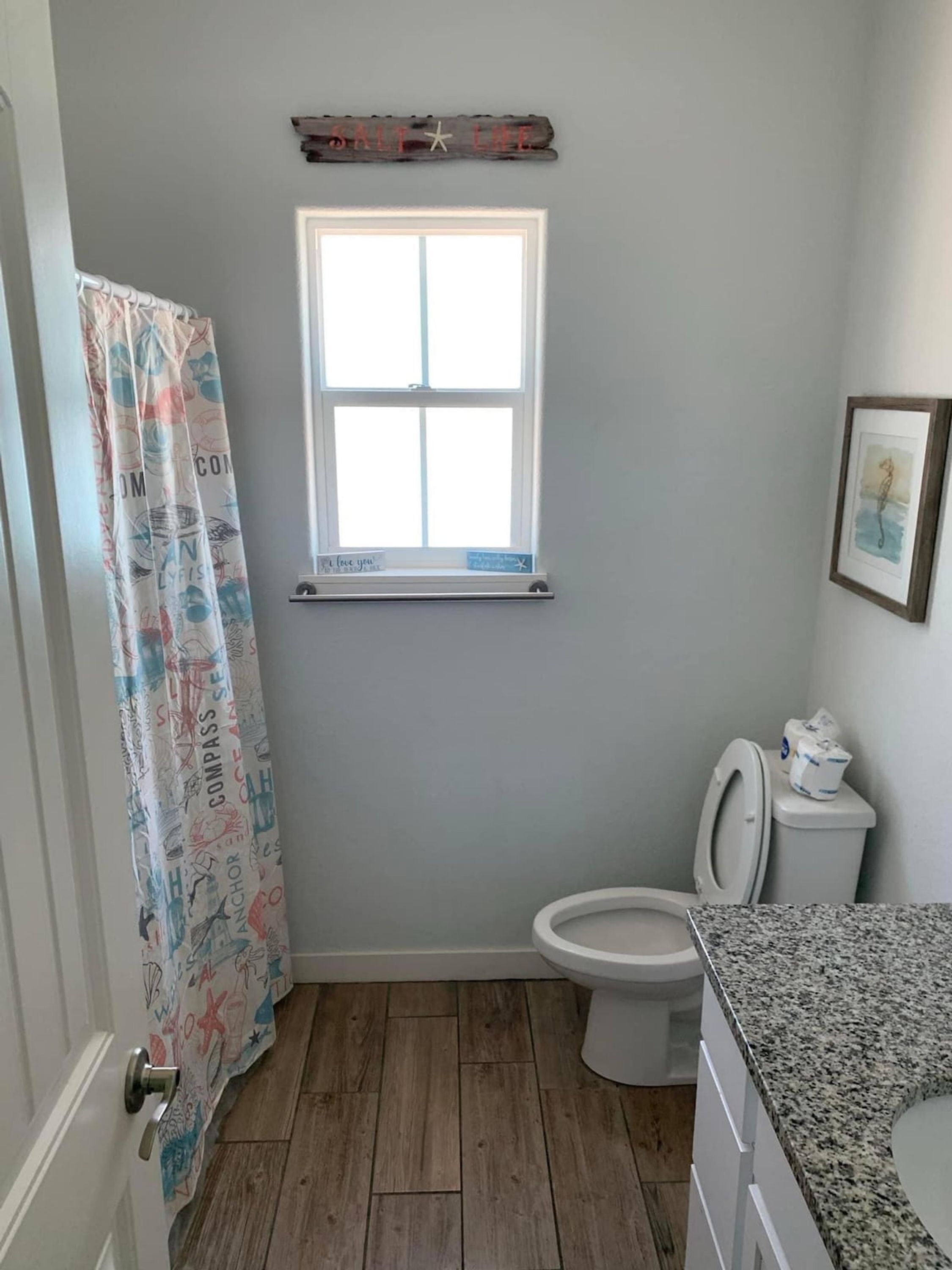 A bathroom with a window, a toilet, and a shower curtain.