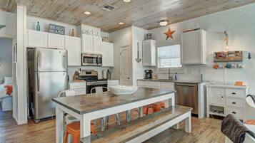 A modern kitchen with white cabinetry, a wooden island, and a star decoration on the wall.