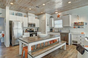 A modern kitchen with white cabinetry, a wooden island, and a star decoration on the wall. - Beach Please- Family Friendly Community Pool (Port Aransas)