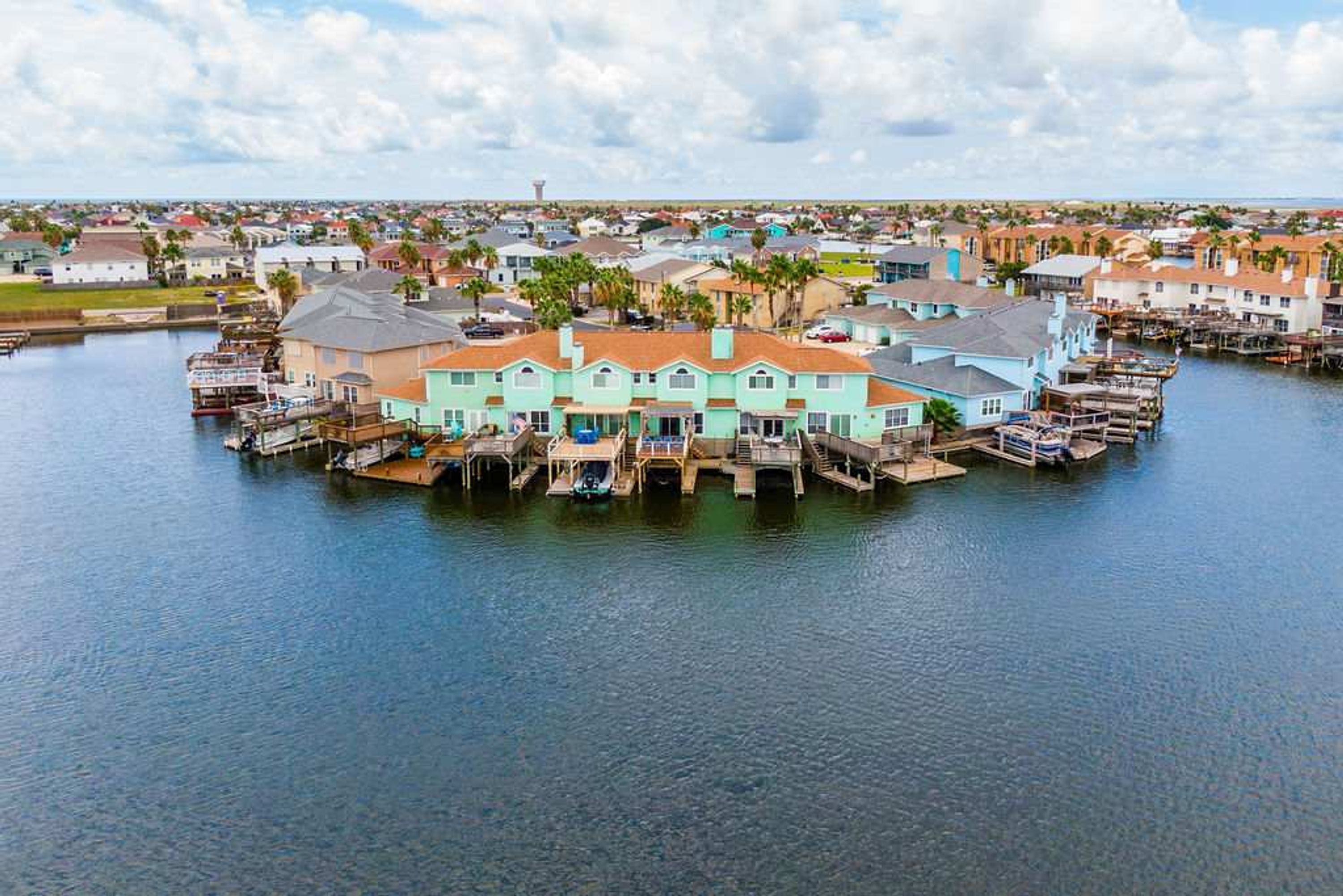 A waterfront property with a large house featuring multiple decks and a dock.