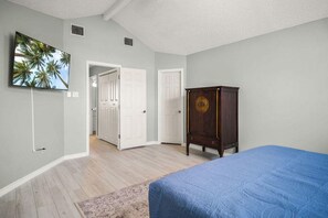 A bedroom with a bed, a wardrobe, a door leading to another room, and a wall-mounted TV. - Shore Thing Waterfront Dock Family Fun (Corpus Christi)