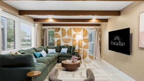 A living room with a sectional sofa, a coffee table, and a wall-mounted TV. - Scottsdale Retreat Pool Pickleball Spa (Scottsdale)