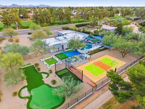 Eine Vogelperspektive eines Wohngebiets mit Schwimmbad, Tennisplatz und Golfplatz.