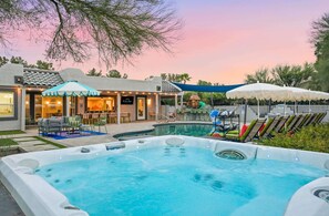 Ein Garten mit Swimmingpool, Sitzgelegenheit im Freien und einer überdachten Terrasse.