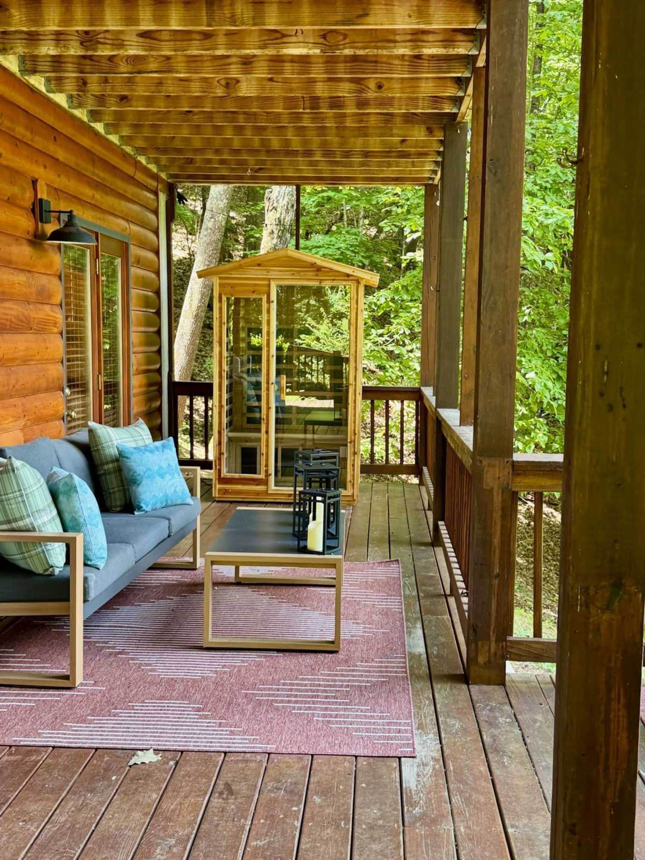 Eine Holzhütte mit Veranda, einer Couch, einem Tisch und einer Glashaube.