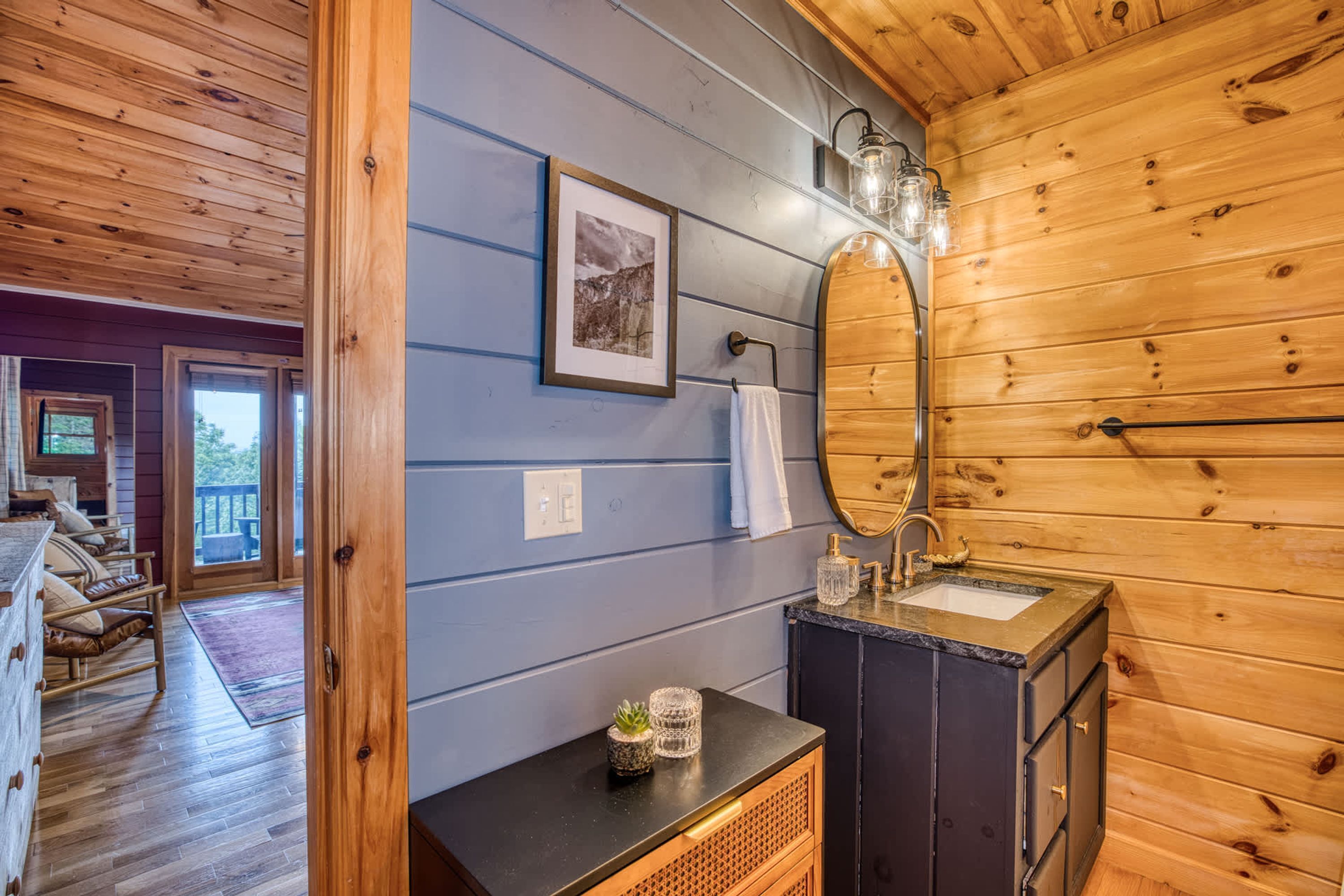 A wooden interior with a bathroom featuring a sink, mirror, and towel rack.