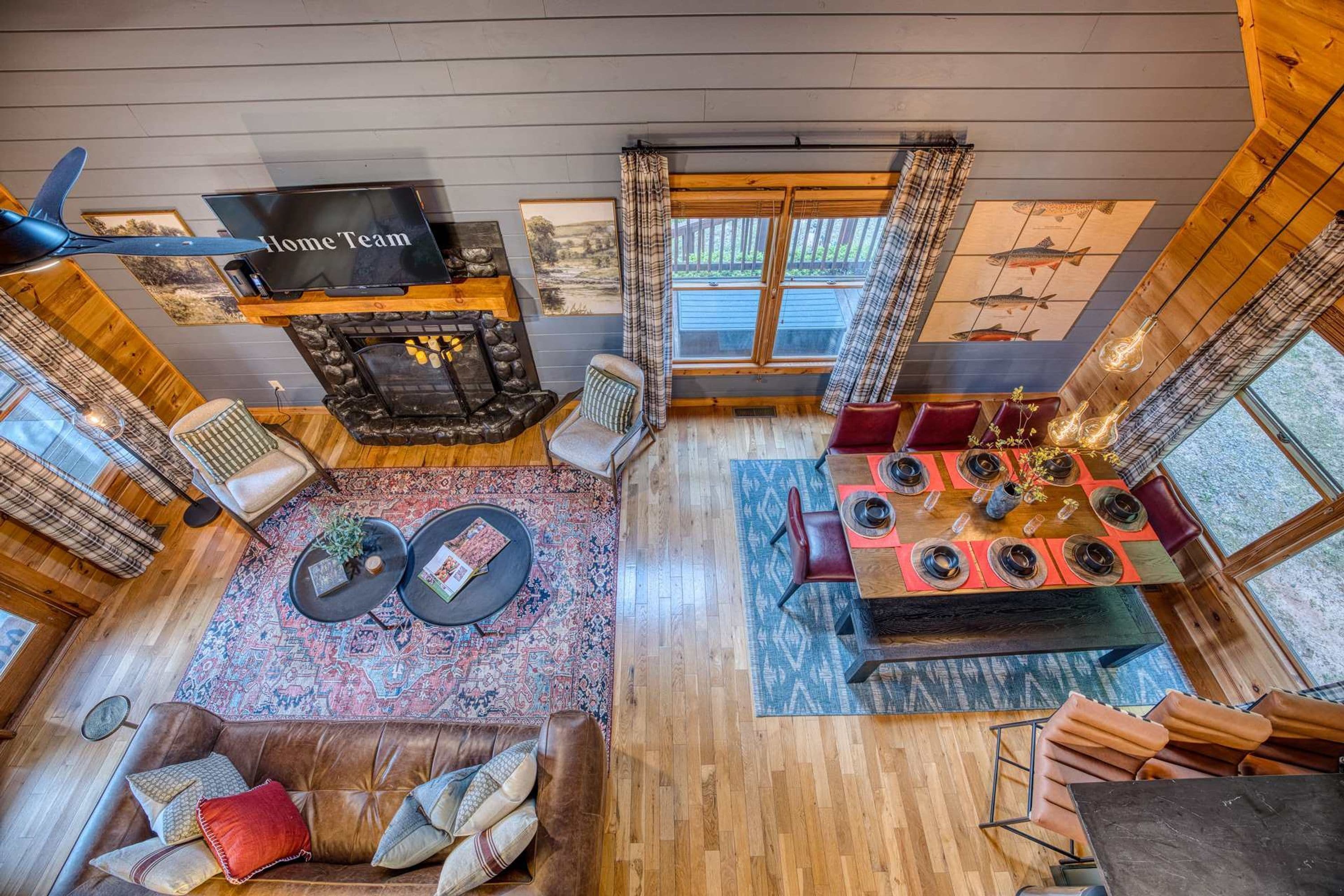 A spacious living area with a fireplace, a dining table set for four, and a television mounted on the wall.