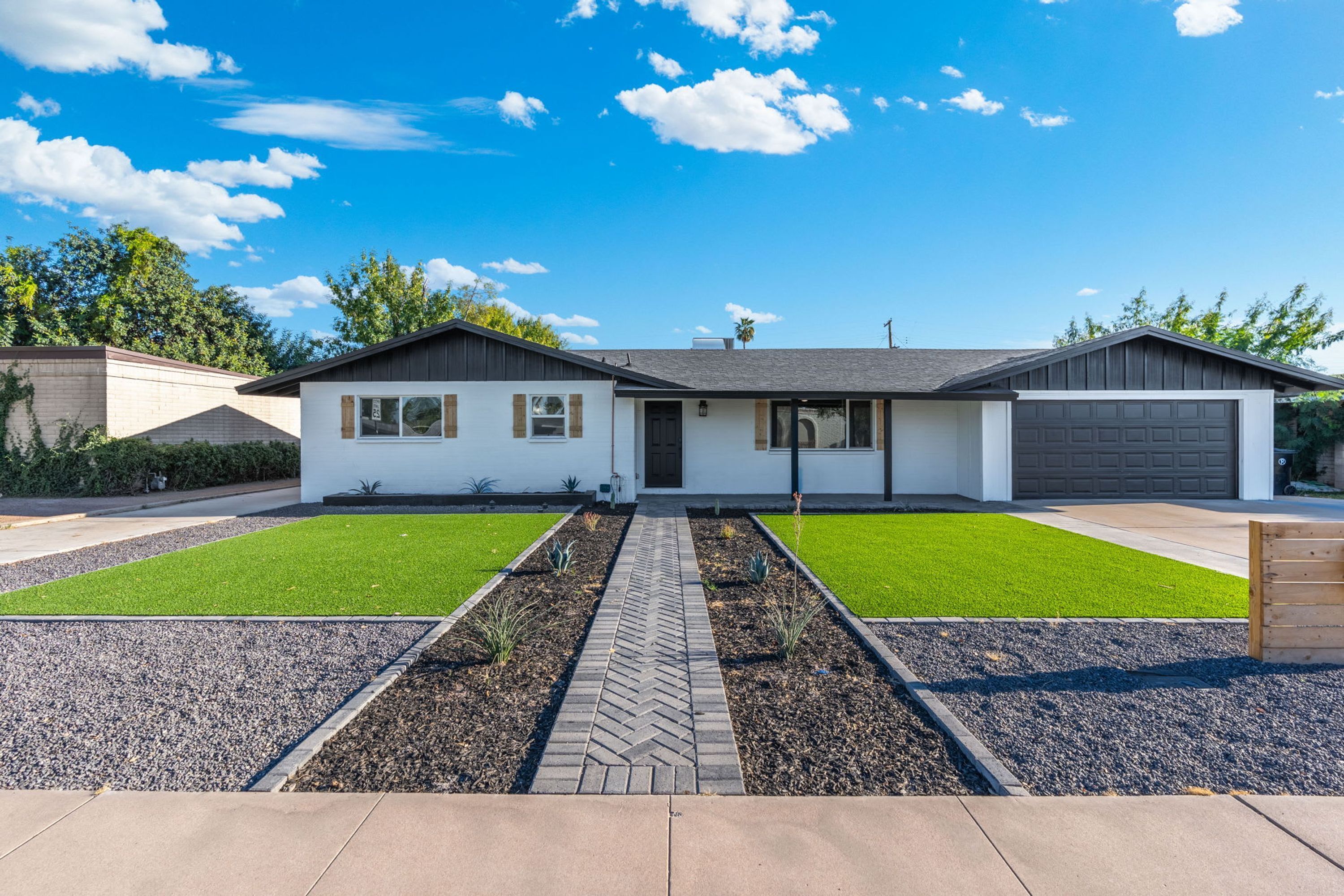 A two-story house with a garage, a front lawn with a pathway, and a clear sky.