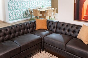 A dark brown leather sectional sofa with a tufted design, positioned in a room with a dining area in the background. - Sleeps 16 Heated Pool Arcade Backyard Resort (Mesa)