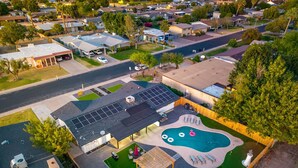 An aerial view of a residential area with a house featuring a swimming pool, solar panels, and outdoor seating. - Sleeps 16 Heated Pool Arcade Backyard Resort (Mesa)