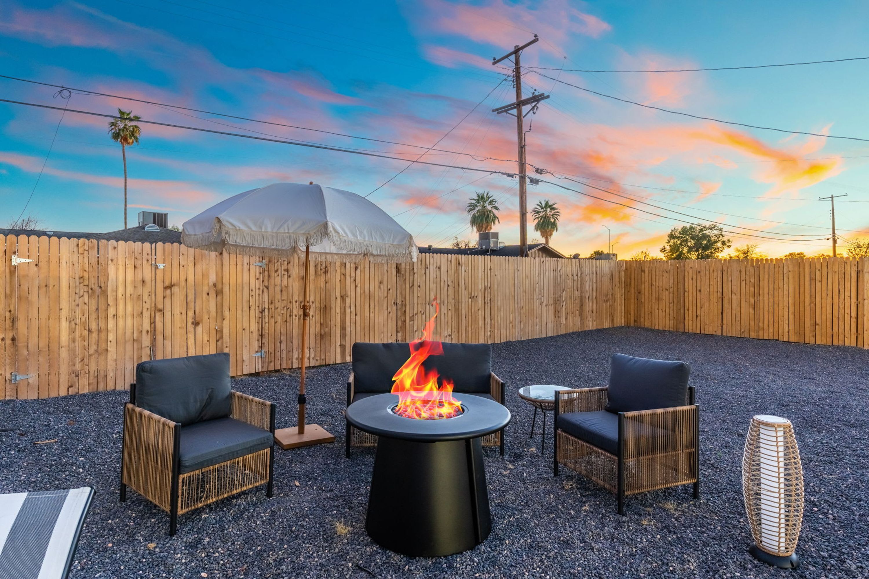 An outdoor seating area with a fire pit, chairs, and a table.