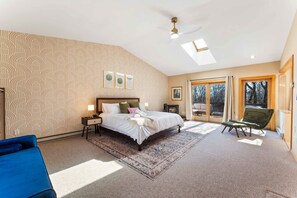 A bedroom with a large bed, a nightstand, a desk, a chair, a ceiling fan, and a view of the outdoors through a sliding door. - 4 Br Mtn Cabin Sauna Hot Tub Fire Pit Putt Putt (Albrightsville)