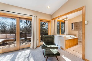 A modern interior with a green chair, a bathroom with a sink, and large sliding glass doors leading to an outdoor area. - 4 Br Mtn Cabin Sauna Hot Tub Fire Pit Putt Putt (Albrightsville)