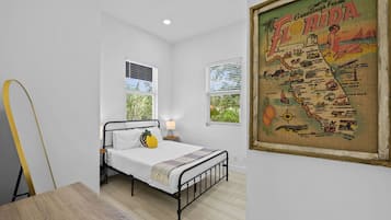 Ein Schlafzimmer mit einem Bett, einem Nachttisch, einer Lampe und einer Karte von Florida an der Wand.