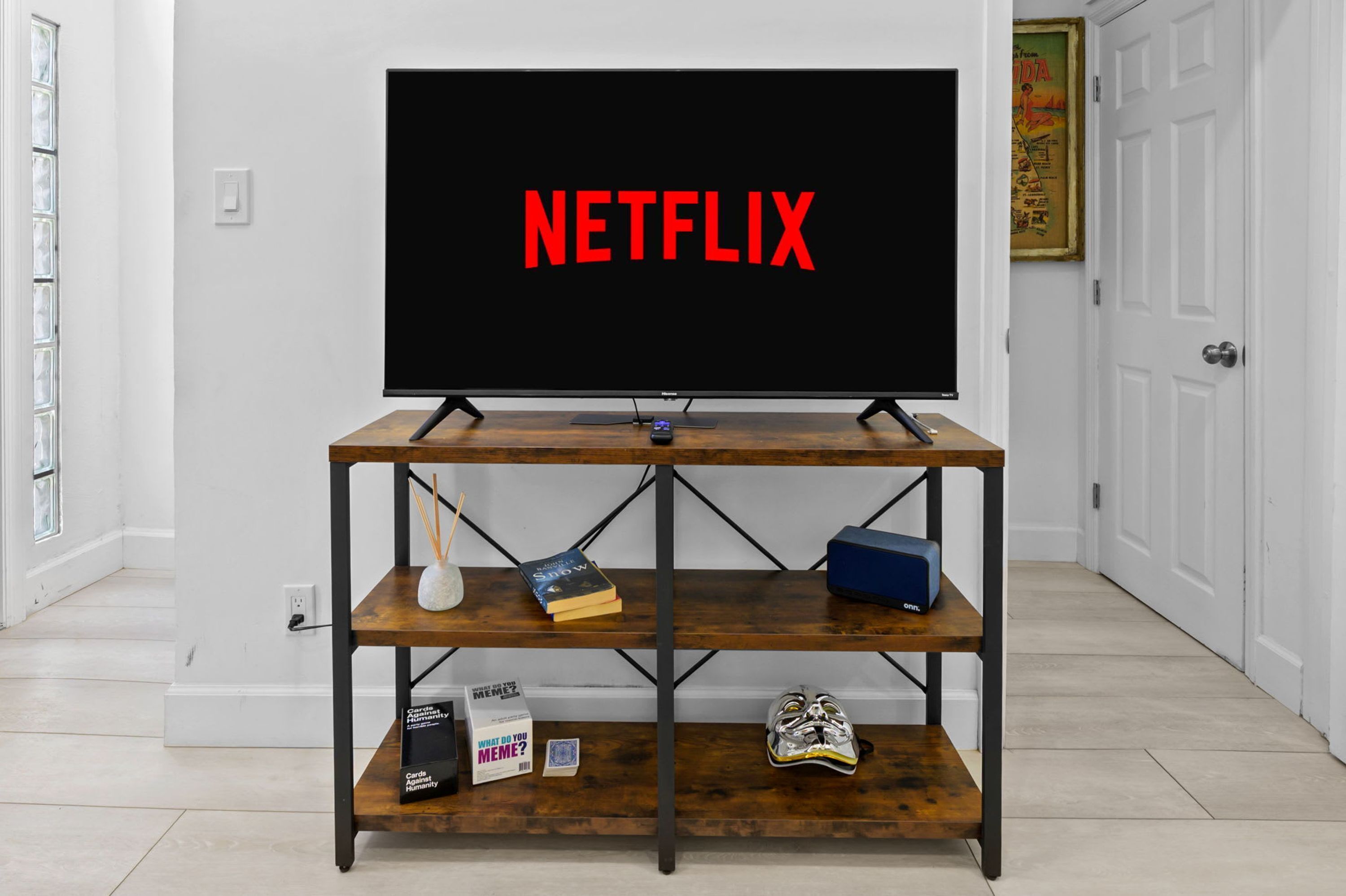 Un téléviseur posé sur un meuble en bois, avec le mot « NETFLIX » affiché à l’écran.