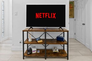 A television on a wooden stand with the word 'NETFLIX' on the screen.