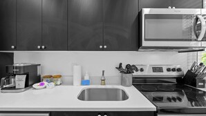 A modern kitchen with dark cabinets, a built-in microwave, a coffee maker, and a stainless steel sink. - Pineapple Paradise 1 13 min to Beach Fire Pit (Sarasota)