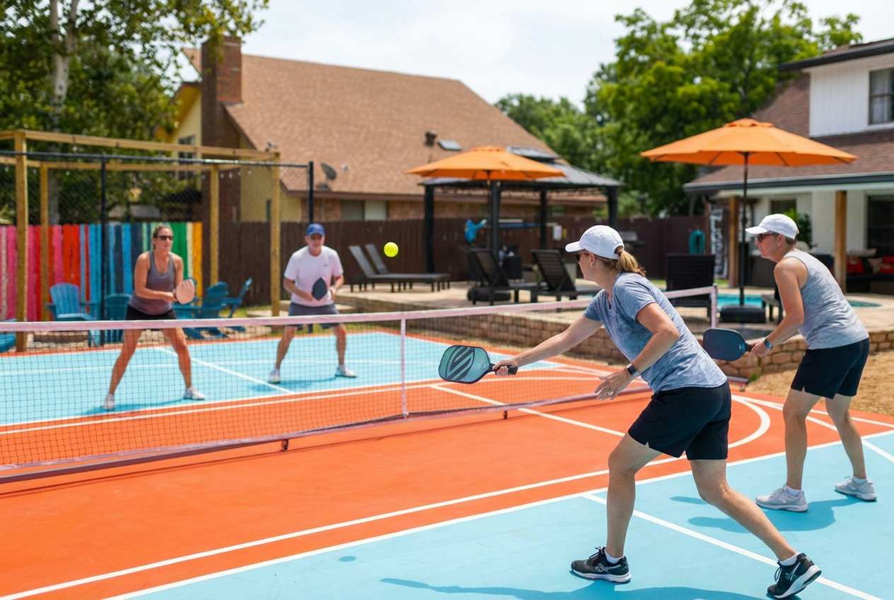 Ein Tennisplatz im Freien mit Netz, umgeben von Stühlen und Sonnenschirmen.