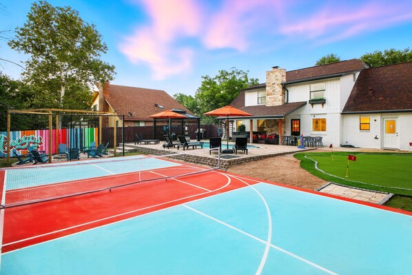 Ein Freizeitbereich im Freien mit Basketballfeld, Sitzgelegenheiten und einem kleinen Schwimmbecken.