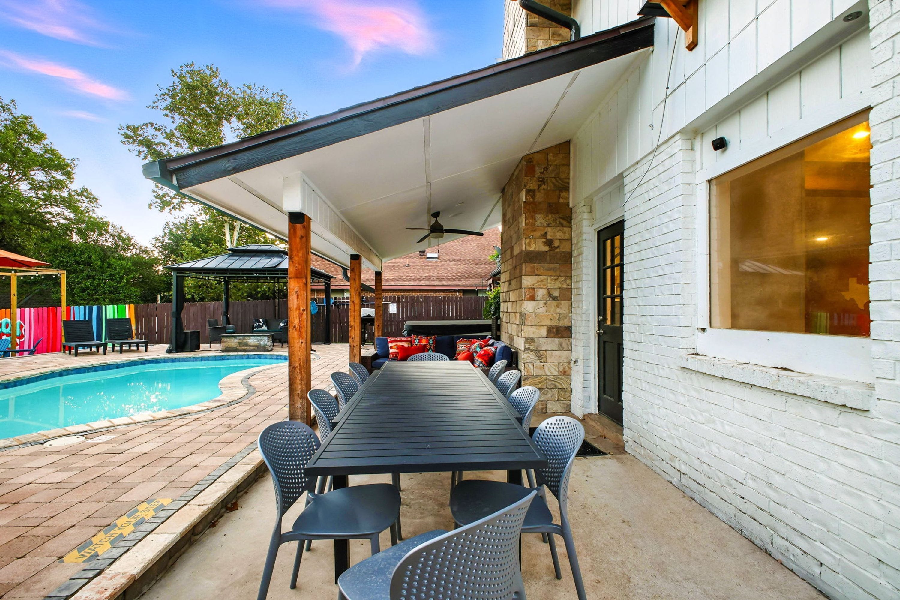 A covered patio with a pool, outdoor seating, and a stone wall.