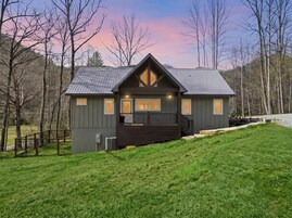 A two-story house with a dark exterior, a front porch, and a small deck.