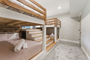Camera con letto a castello, soffitto in legno, scala e tappeto bianco soffice.