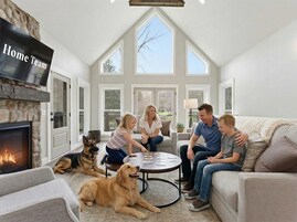 A family in a living room with a fireplace, large windows, and a stone accent wall.