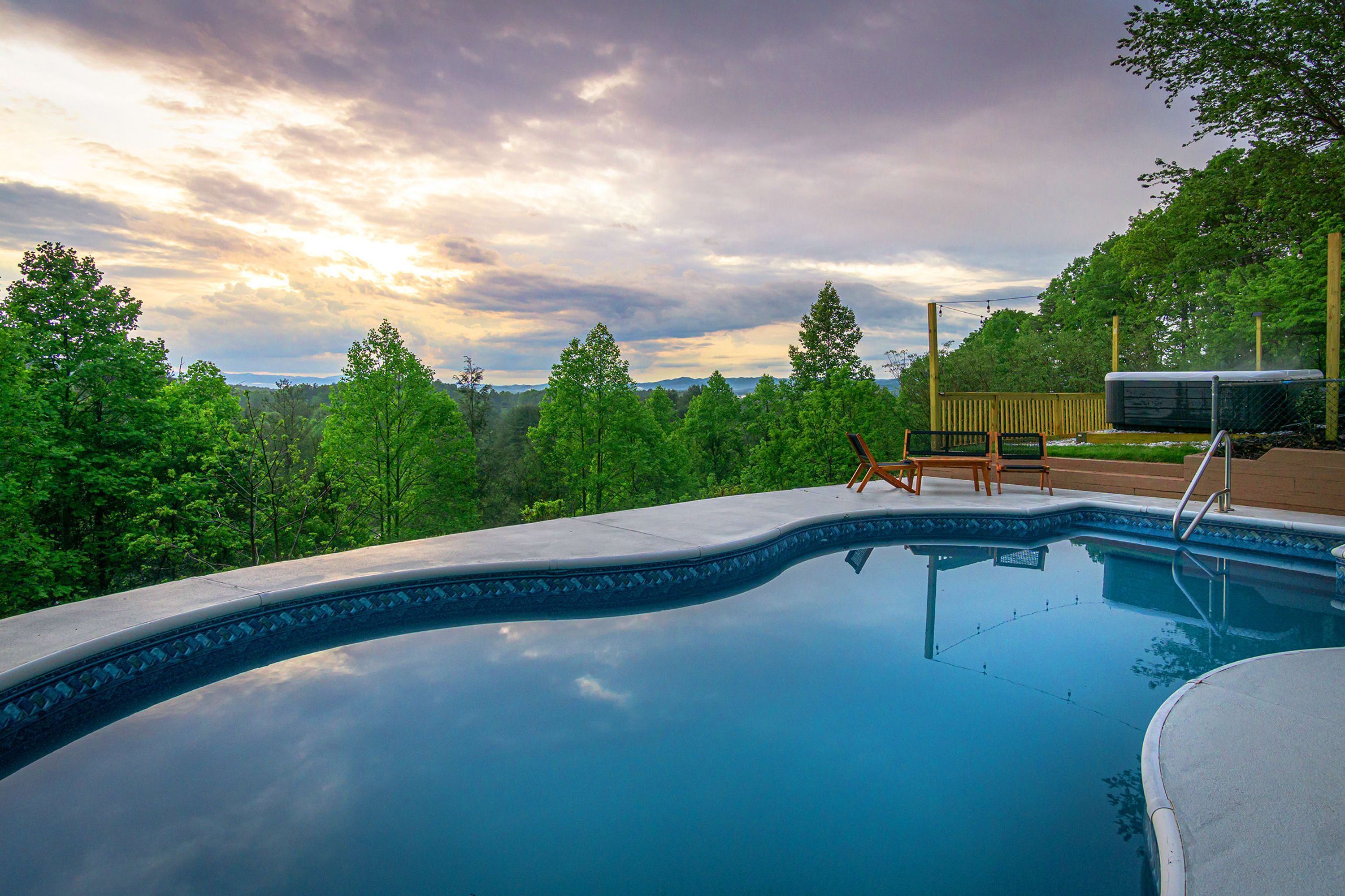 A swimming pool with a view of a forest and mountains in the background.