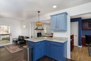Une cuisine moderne avec des armoires bleues, des comptoirs en granit et un luminaire suspendu.