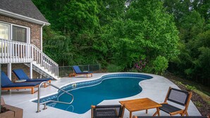 Un jardin avec une piscine, des chaises longues et une terrasse en bois.