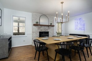 Une cuisine moderne avec un mur en briques, une table à manger en bois et des chaises noires.