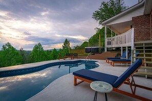 Piscina com espreguiçadeiras e área de estar coberta.