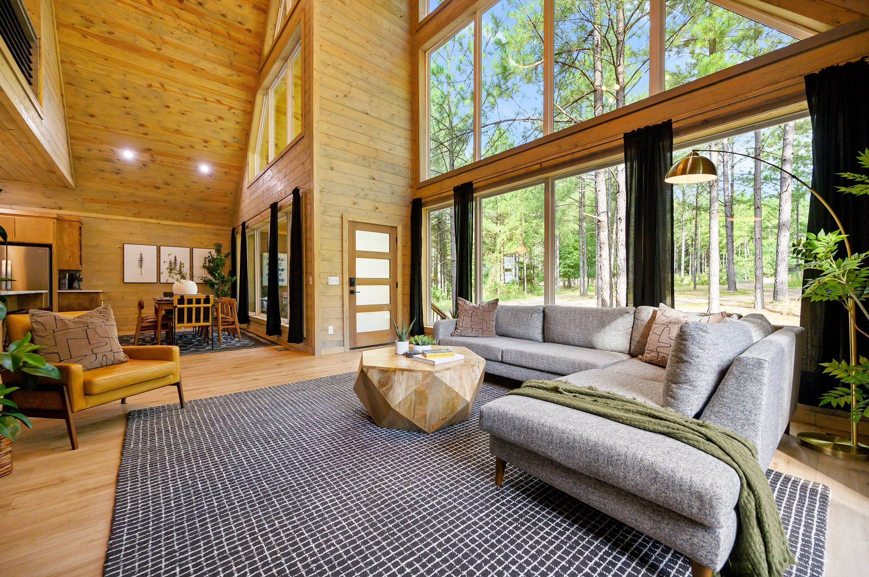 A spacious living room with a large window, a sofa, a coffee table, and a dining area with chairs.