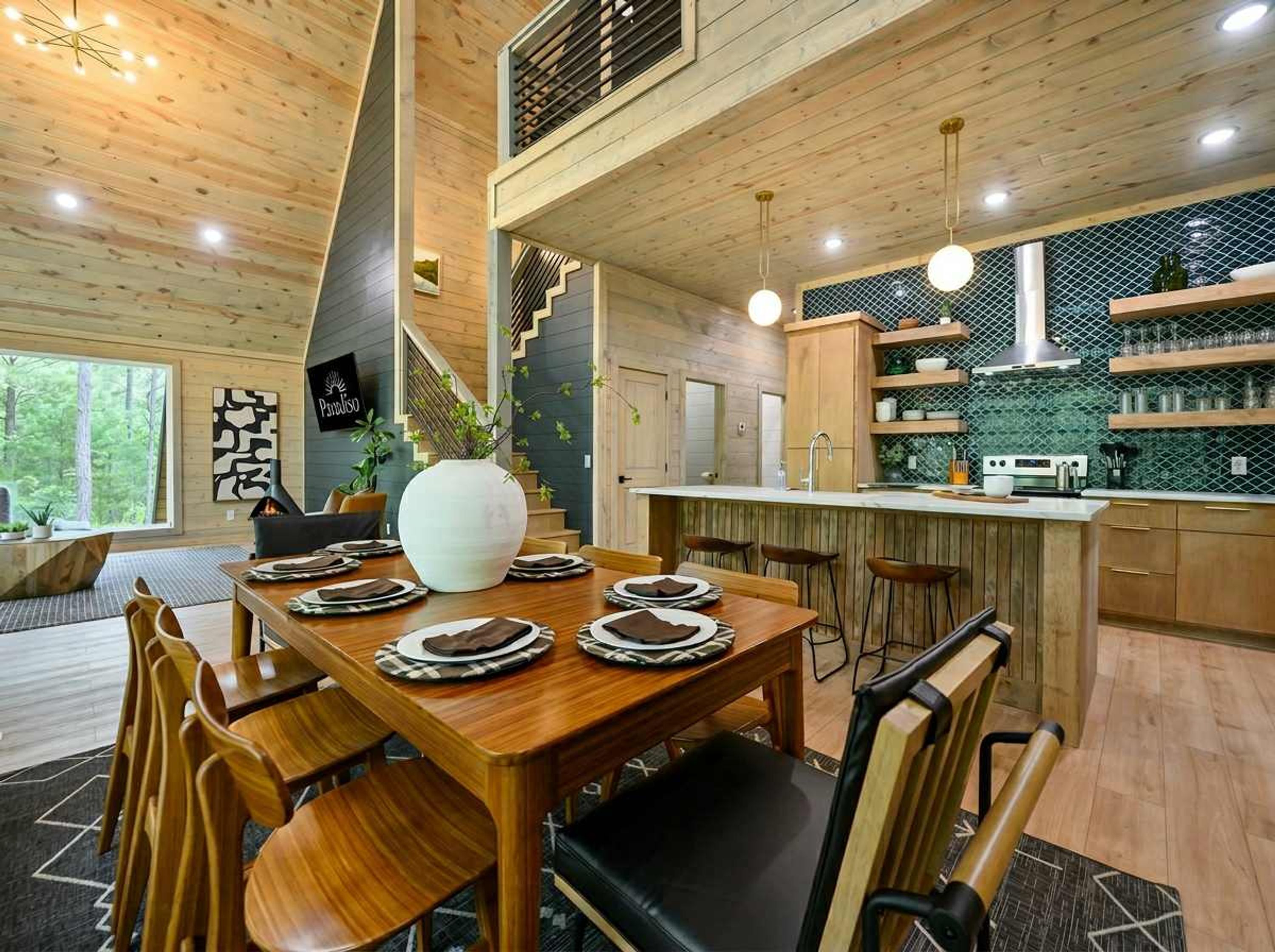 A modern kitchen with wooden cabinetry, a central island, pendant lighting, and a view of the outdoors.