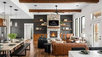 A modern interior with a stone fireplace, wooden beams, and a dining area with benches.